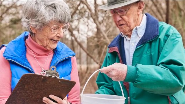 Earl and Sue outdoors with a clipboard and bucket